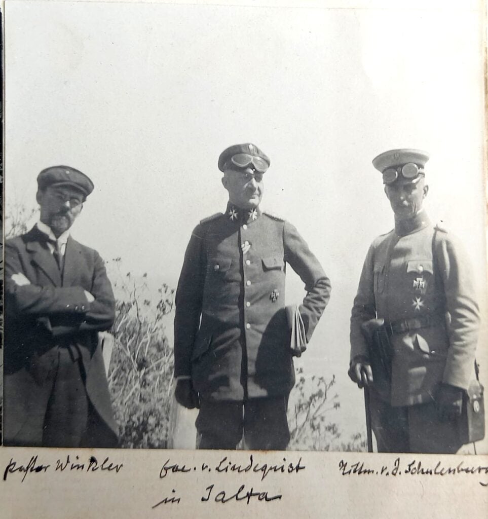 Three European men, one in a suit and two in military uniform, posed for the camera